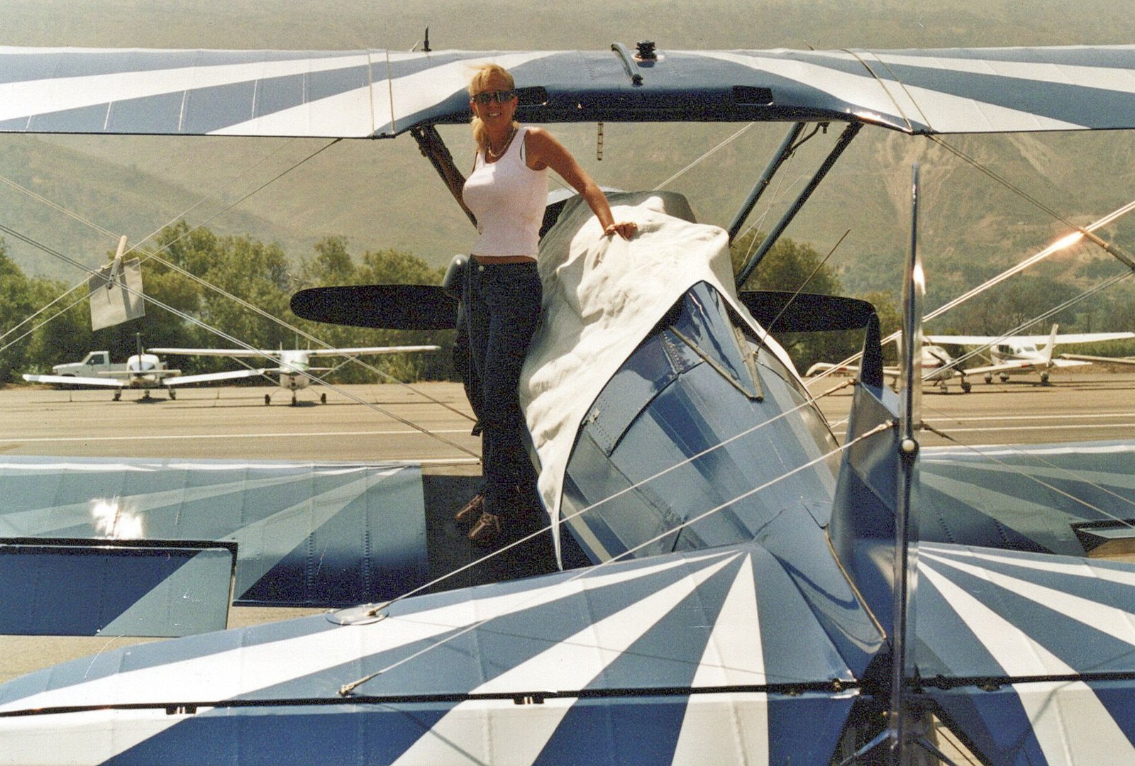 Micki standing at the cockpit of the family Boeing Stearman PT-17 in its blue-and-silver sunburst scheme, after Captain John's re-cover.