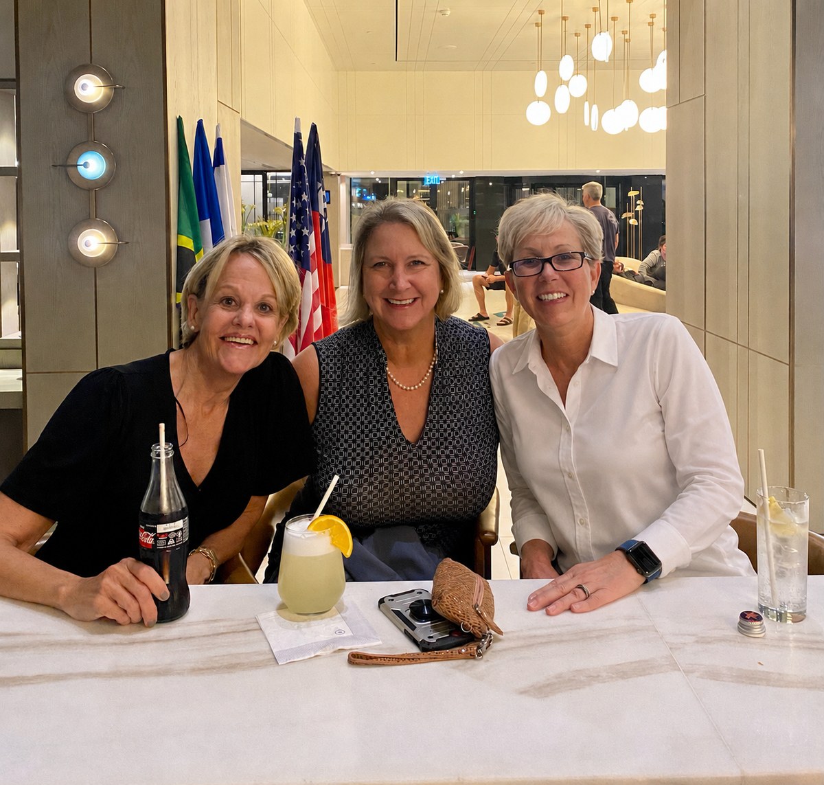 The three friends at dinner in the hotel — Coca-Cola bottle, limonana, and the flags of the lobby behind them.